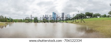 Panorama downtown Houston with storm cloud sky and rare high water flood on Eleanor Park because of Harvey Tropical Storm. Green park lawn and modern skylines from the fourth-most largest city in US