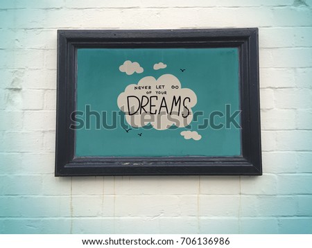Never let go of your dreams cloud and sky in black frame on white wall background