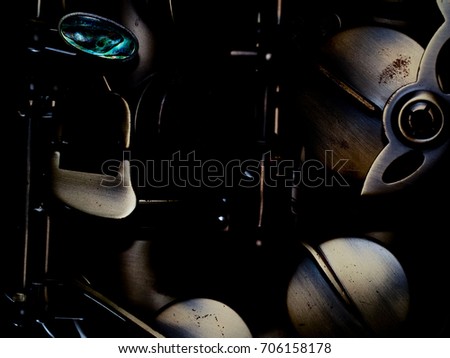 Fragment of a saxophone valves in gold tones with selective focus on a dark background