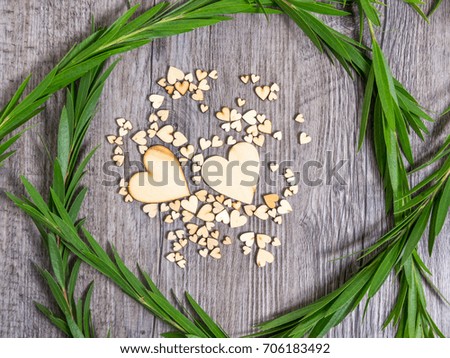 Heart shape surrounded by green foliage on wood texture background, Studio shot on wooden background.