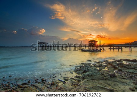 Sunset at beach with fisherman boat parking and jetty . Mersing Johor. This image may contain noise ,blurry clouds due to long exposure, soft focus and poor lighting