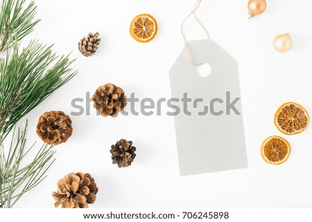 Big price tag with fir branch, pine cones, dry orange and Christmas balls on white background, top view. Flat lay composition