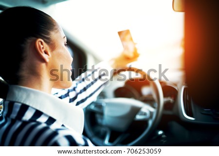 Rear view of a stylish young girl making a selfie in the car.