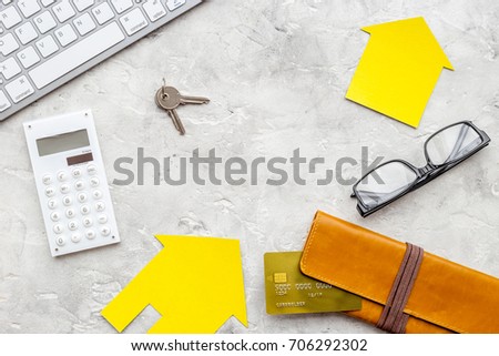 work desk with keyboard, keys and paper figures for selling house set stone background top view space for text