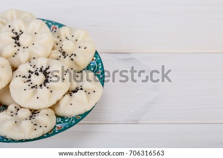 Flower Shaped Persian Sweet Rice Cookies (Naan Berenji) with Poppy Seeds on white wooden background shot from the top and Empty space for typing your text