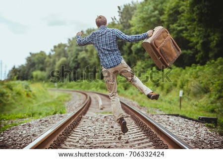 finally holiday, happy man jumping in the air on the rails with a bag 
