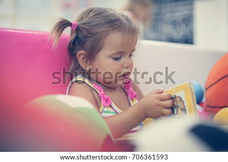 Little girl in playground. Little girl reading picture book.