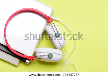 Sound recording idea. Earphones made of plastic with computer. Headphones and silver laptop. Music and digital equipment concept. Electronics isolated on yellow background with copy space, top view