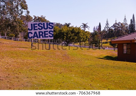 Big religious sign on grass with Christian message. Proselytising roadside sign on the lawn with a background of a fence and tropical Australian trees.