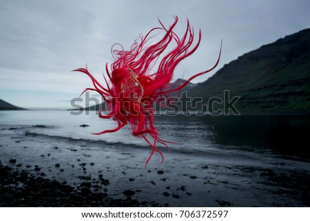 expressive picture of red hair flying through the air in front of dramatic icelandic landscape