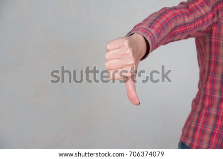 woman showing thumbs down sign in office with copy space.girl dressed in casual clothing. Focus at hands. she giving thumb down as sign of failure on gray background. customers feedback concept