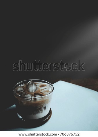 The picture of iced coffee in the glass on black background with sunshine effect. selective focus,  soft tone style
