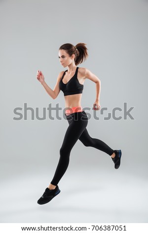 Full length image of a sports woman running in studio over gray background