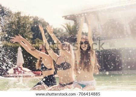Summer holiday travel girls having fun splashing water and playing in the pool feeling happy in amazing resort, sunglasses, chilling at the hotel pool. Best summer vacation ever in the tropical island