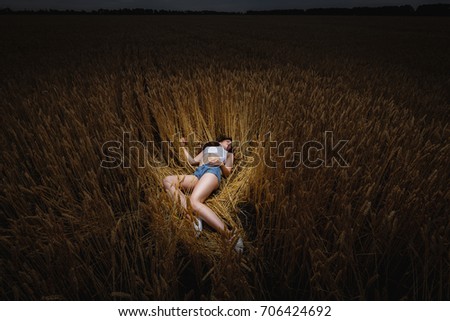 woman is lying in golden field of wheat or barley. alien girl . posing in field. lying attractive sleeping girl. unconscious girl