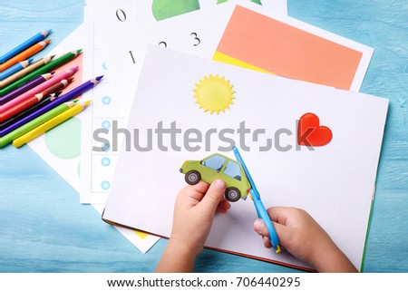 Little boy cutting shapes out of colored paper. Children being creative,