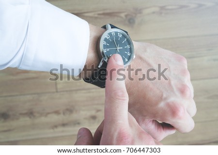 A person pointing at his watch on his wrist with his index finger. Look at the time. Royalty-Free Stock Photo #706447303