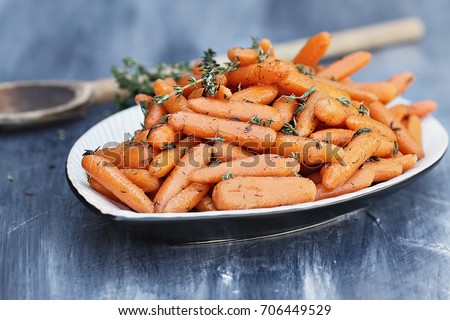 Honey Glazed Baby carrots with wooden spoon for Rosh Hashanah or Thanksgiving Day. Extreme shallow depth of field with selective focus on carrots in foreground of dish.