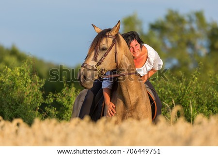 portrait picture of a mature woman on an Andalusian horse