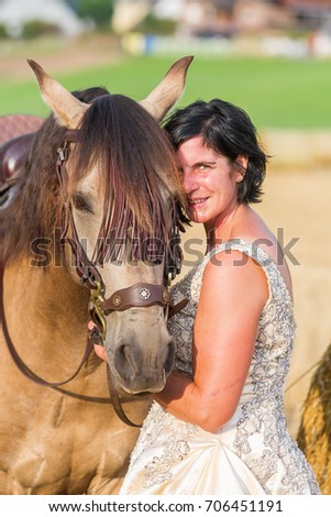 portrait picture of a mature woman with bridal dress and Andalusian horse