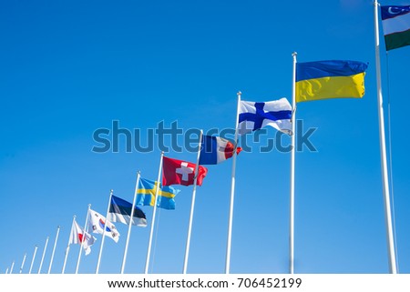 World Flags Blowing In The Wind On blue Sky Background. Flags of many nation