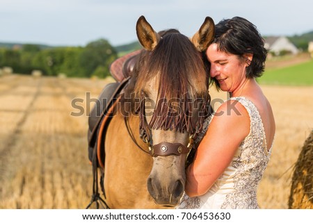 portrait picture of a mature woman with bridal dress and Andalusian horse