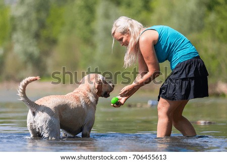picture of a woman who plays with her labrador retriever in a lake