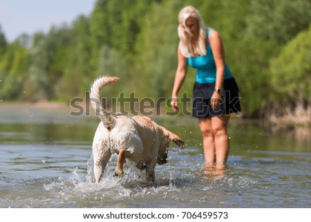 picture of a pretty woman who plays with a labrador dog in a lake
