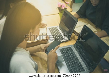 The girl group is researching in the library. Someone researched by smartphone. Someone researched by a notebook computer. Someone research by the book.
