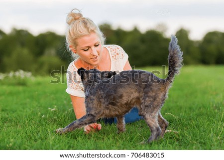 picture of a woman who plays with a terrier hybrid dog on a meadow