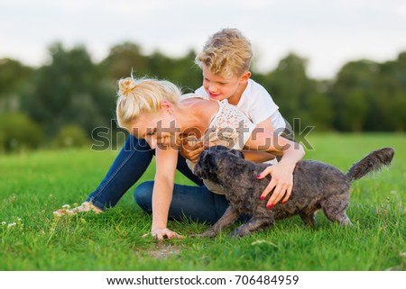 picture of a woman who romps with her son and a dog on the grass