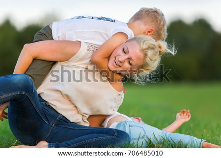 picture of a woman who romps with her two sons on the grass