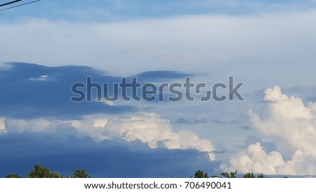 Blue and white fluffy clouds with tree tops
