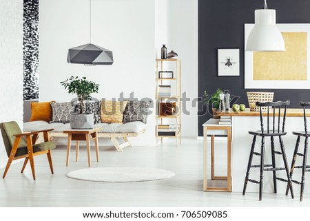 Bar stool at kitchen countertop in multifunctional interior with green chair and sofa