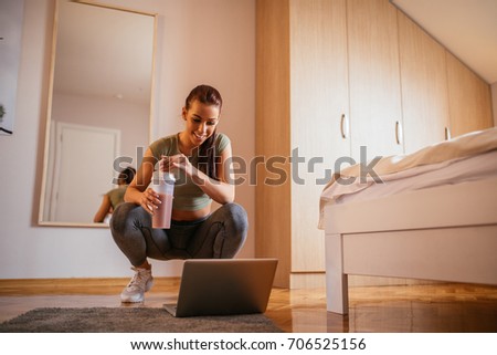 Full length portrait of a smiling young athlete woman using laptop.