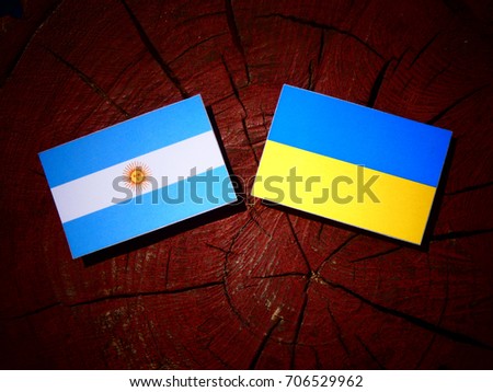 Argentinian flag with Ukrainian flag on a tree stump isolated
