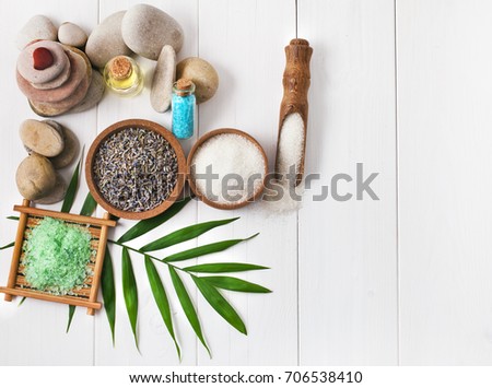 Spa stones with lavender flowers and sea salt on a white wooden background.