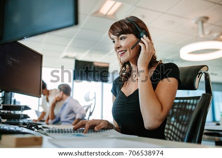 Call center business woman talking on headset. Caucasian female in customer service position talking on the phone. Royalty-Free Stock Photo #706538974