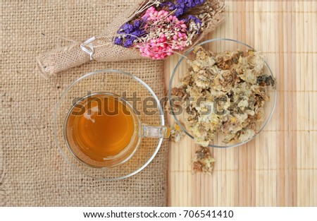 Chrysanthemum juice in clear glass cup and dried Chrysanthemum flower on wood plank background. Top view.