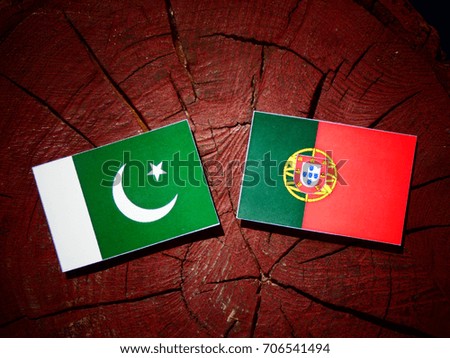 Pakistan flag with Portuguese flag on a tree stump isolated