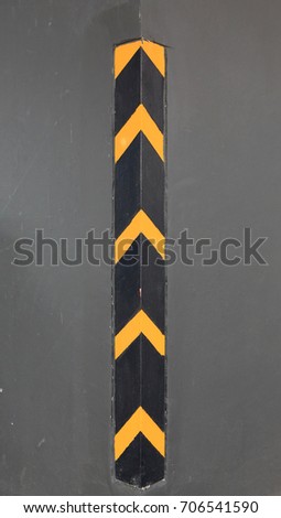 Warning black and yellow traffic sign on angle concrete wall