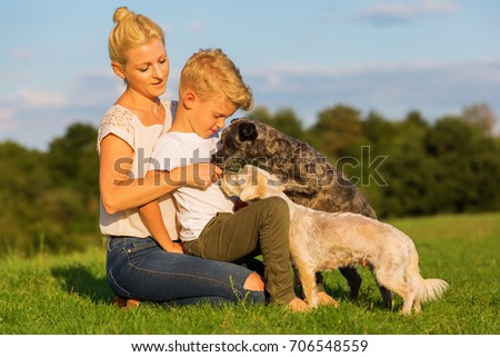 picture of a mother with her son playing with two small dog outdoors