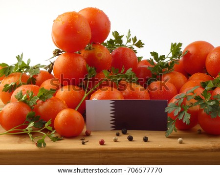 Qatari flag on a wooden panel with tomatoes isolated on a white background