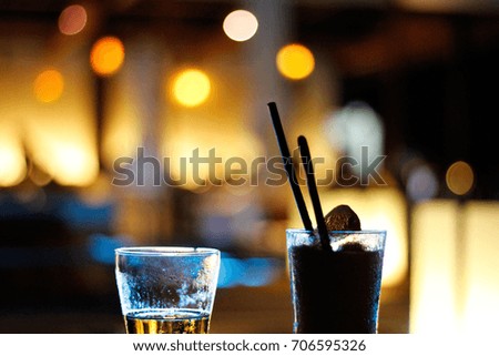 a glass of beer and a glass of mix fruits beverage with bokeh light background.