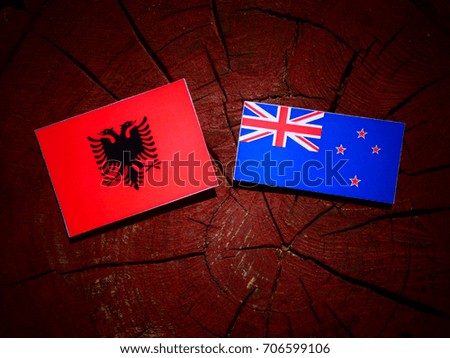 Albanian flag with New Zealand flag on a tree stump isolated