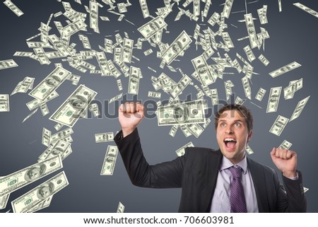 Digital composite of Excited business man with money rain against blue background