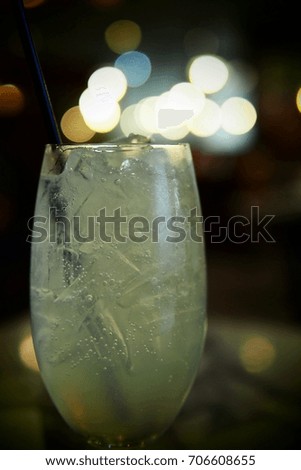 A glass of soda water with ice on bokeh background and blurred texture