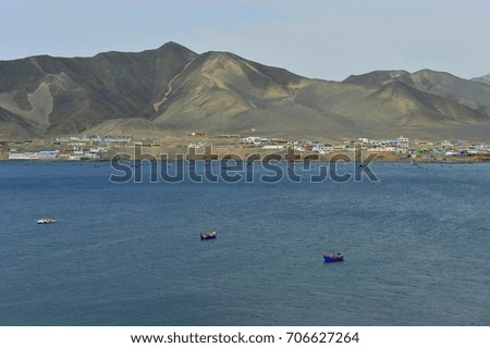 Peruvian beautiful and scenic ocean beach landscape around midday / in the background the desert with mountains 