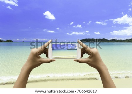 Taking a photos by smartphone of seascape clear water and beach with blue sky in summer. Landscape.