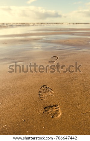 Shoe footprint imprints on fresh sand on a sunny golden day. Footsteps disappearing into the distance. Freedom from depression.